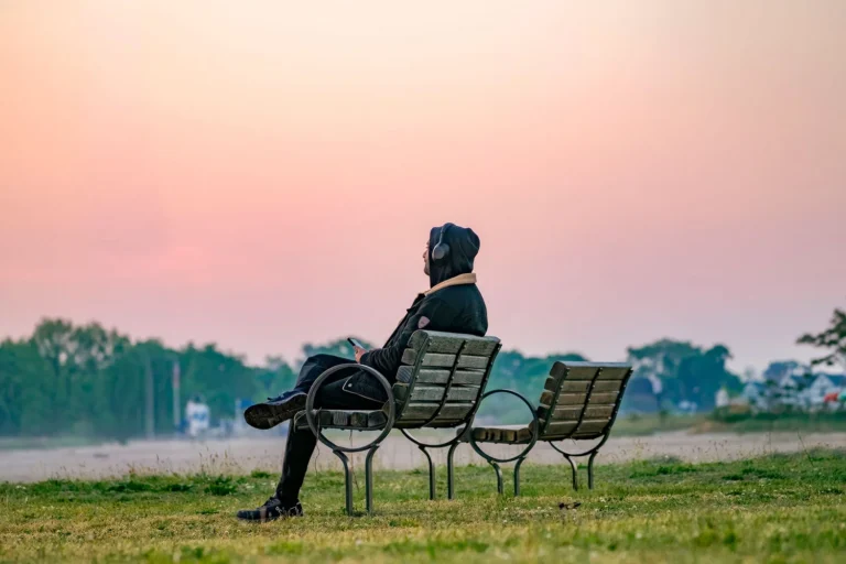 Hombre sentado en un banco escuchando música triste